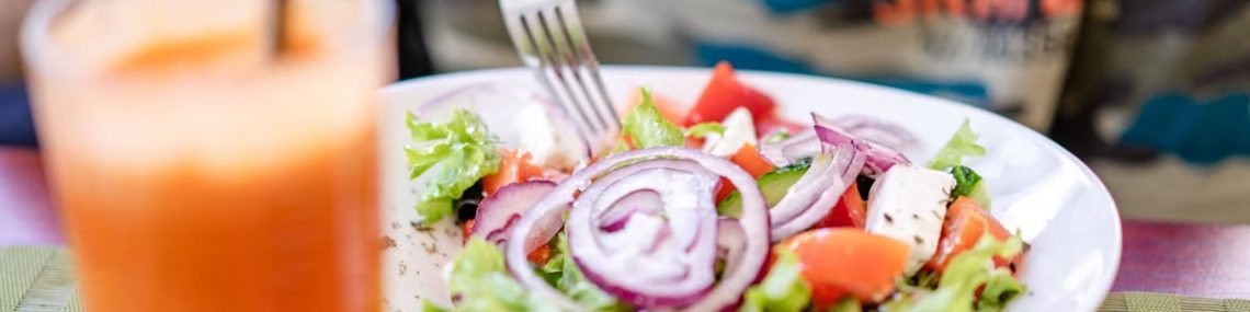Colorful salad with fresh vegetables and a refreshing drink on a table.